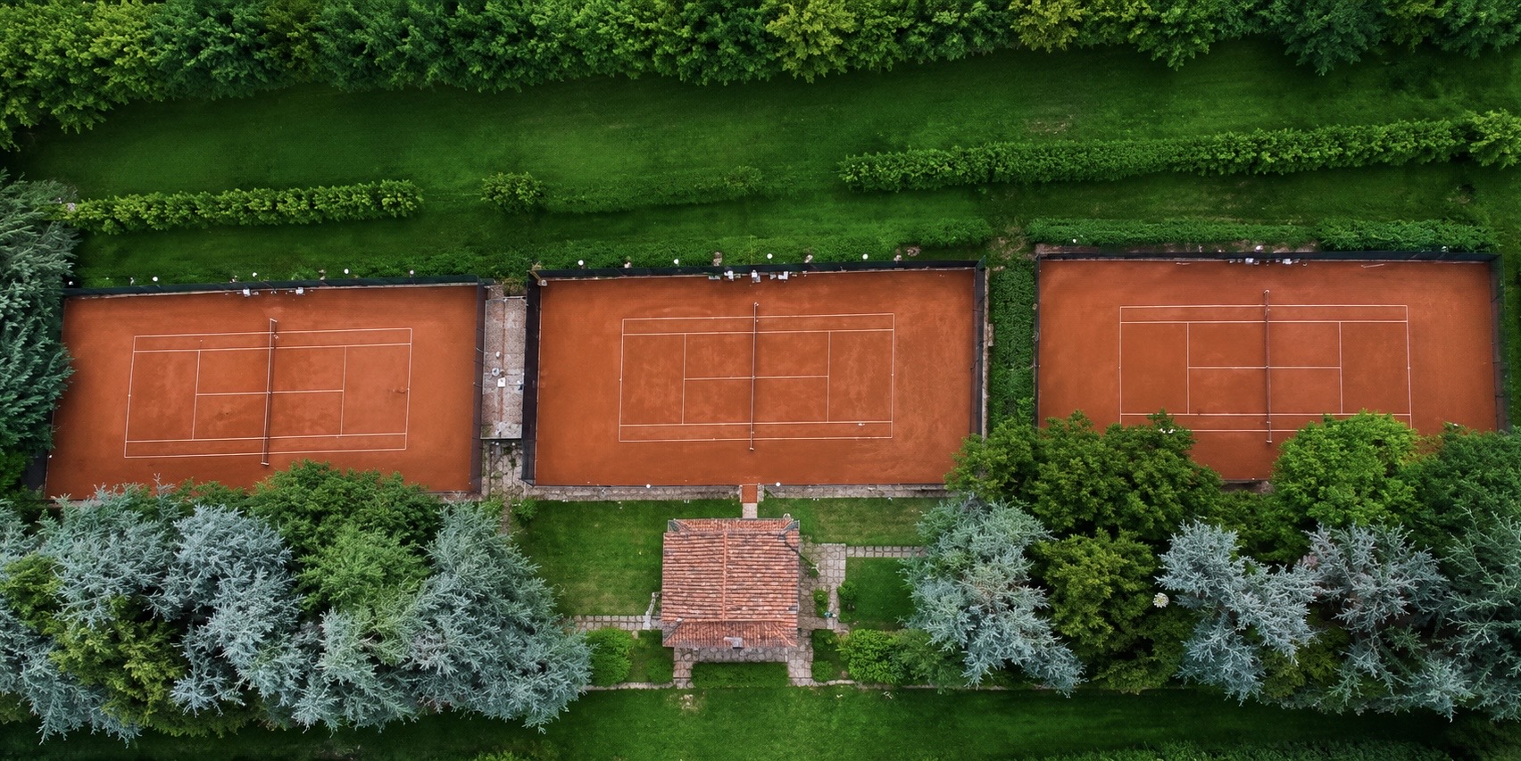 Vista aerea dei tre campi da tennis in terra rossa con clubhouse
